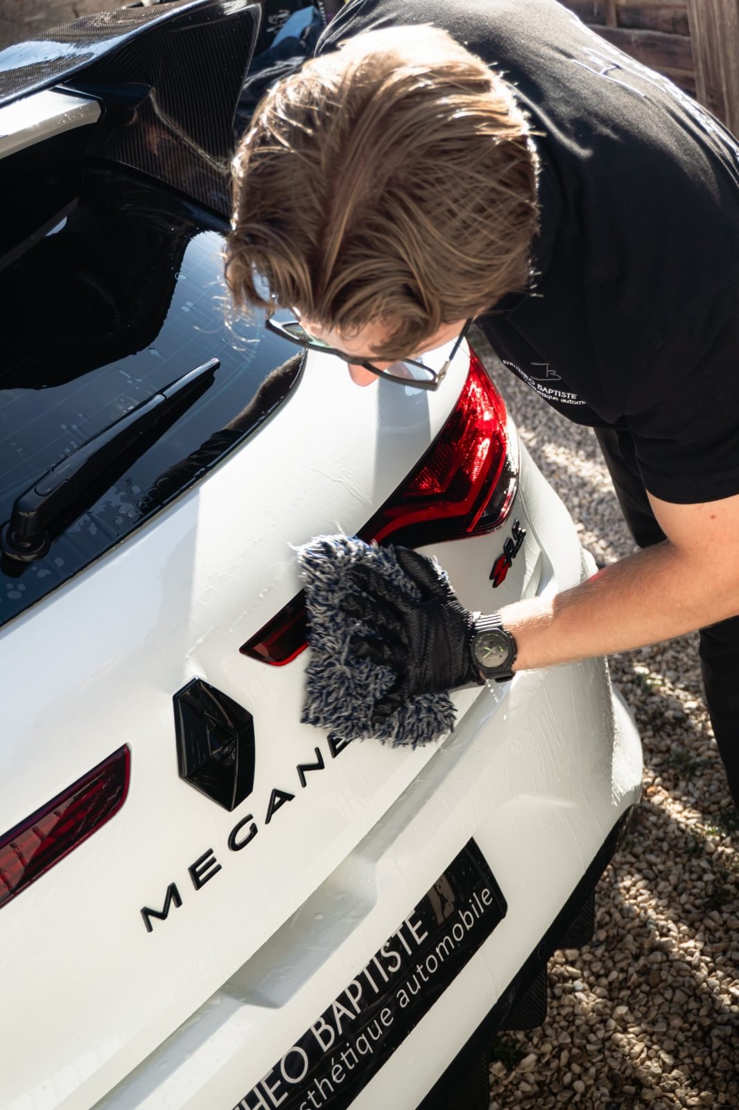 Théo Baptiste nettoie une Renault Mégane R.S. blanche